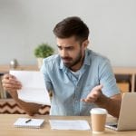 A young man reads a customer service letter that isn’t clear and creates confusion.