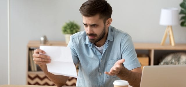 A young man reads a customer service letter that isn’t clear and creates confusion.