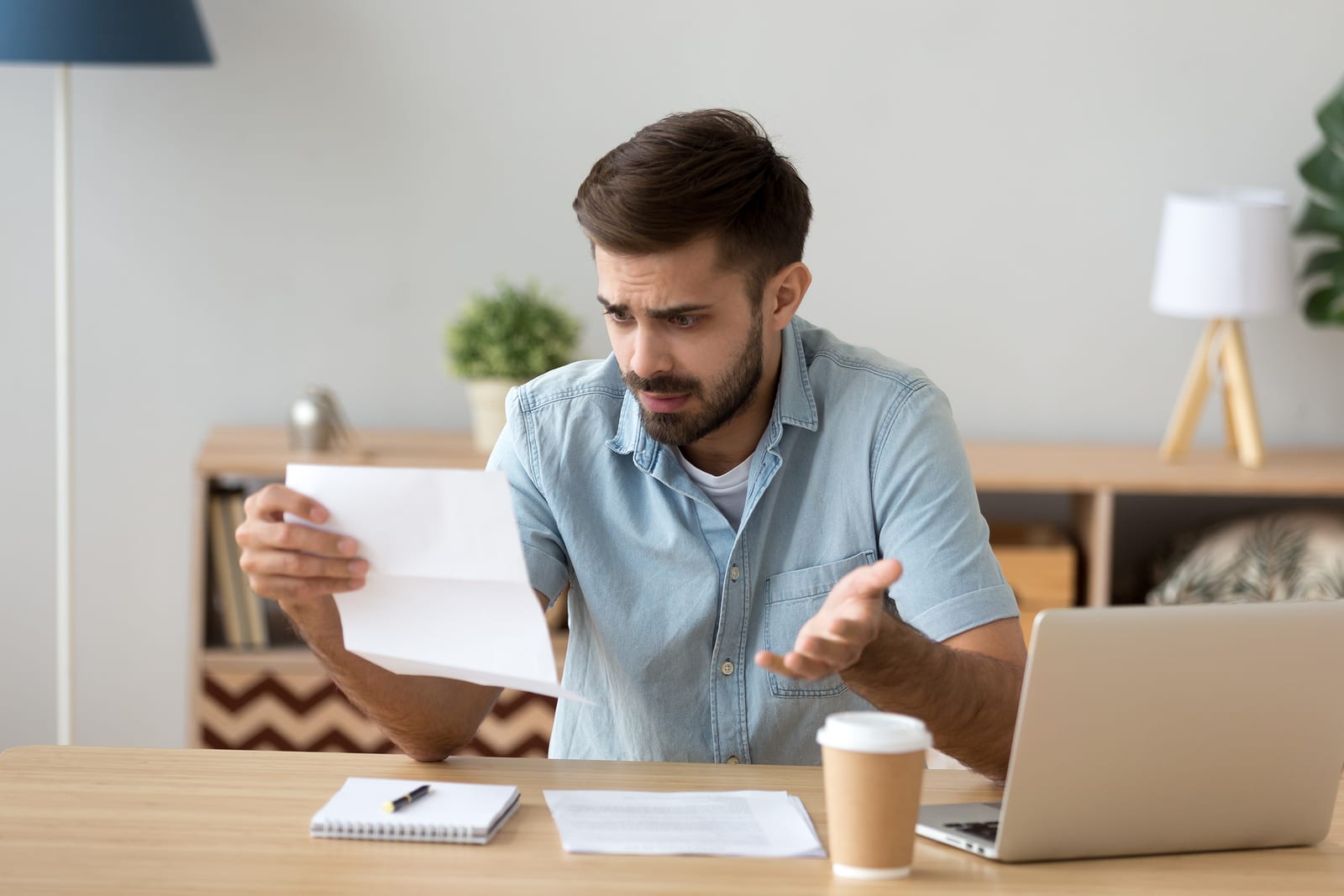 A young man reads a customer service letter that isn’t clear and creates confusion.