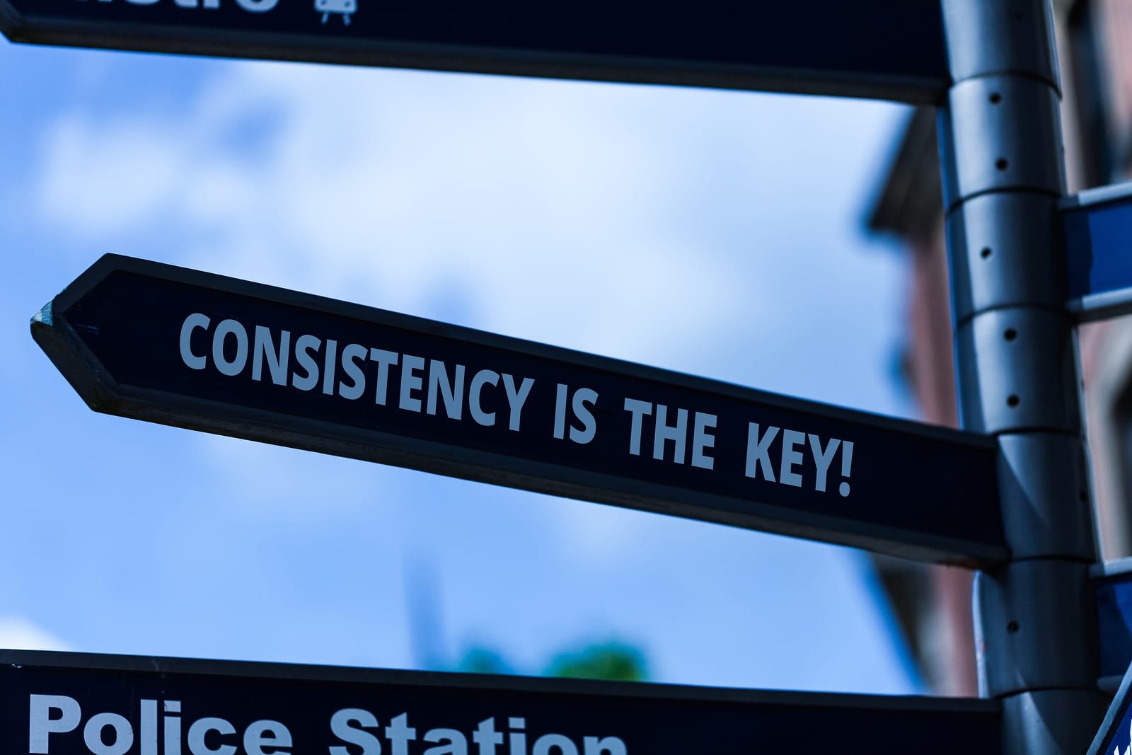 A road sign points to the left and says Consistency is the Key!