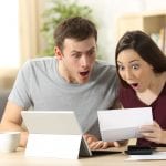 Amazed couple reading together a letter sitting in a desk at home