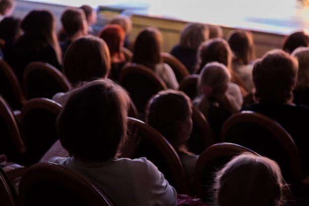 The audience in the theater watching a play. The audience in the hall: adults and children.