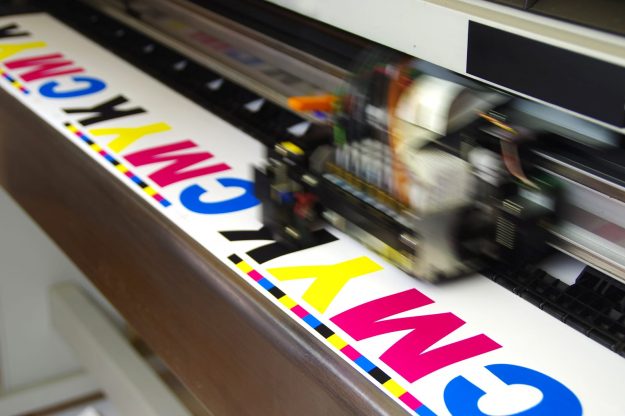 bigstock–221653537 Plotter head printing CMYK test on white paper. Digital large inkjet machine working.