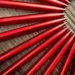 A lot of red pens in a circle on a black wooden background. Concept office or school knowledge day the first of September. great pattern beckground