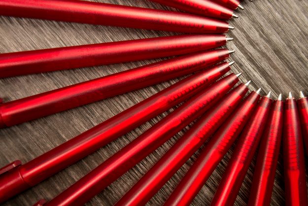 A Lot Of Red Pens In A Circle On A Black Wooden Background. Conc A lot of red pens in a circle on a black wooden background. Concept office or school knowledge day the first of September. great pattern beckground