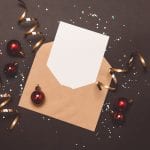 A holiday mailer with confetti and streamers sits on a gray background.