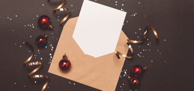 A holiday mailer with confetti and streamers sits on a gray background.