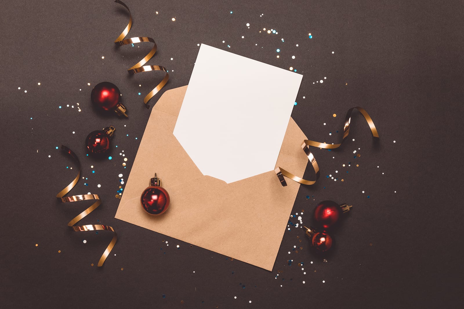 A holiday mailer with confetti and streamers sits on a gray background.