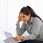 Happy young woman enjoying good news in writing. The girl reads a letter with good news sitting on the couch. An euphoric girl is happy after reading good news in a written letter, approving a loan.