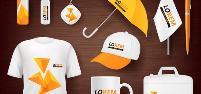 A t-shirt, mug, bag, hat, umbrella, flag, and office supplies all display custom orange logos to promote a business.