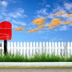 a red postbox and brown envelope with blue sky