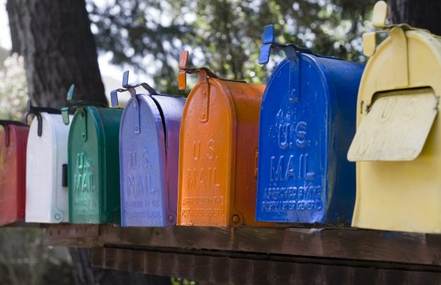 Row of mail boxes A row of multicolor mail mailboxes all have U.S. Mail stamped on the front.