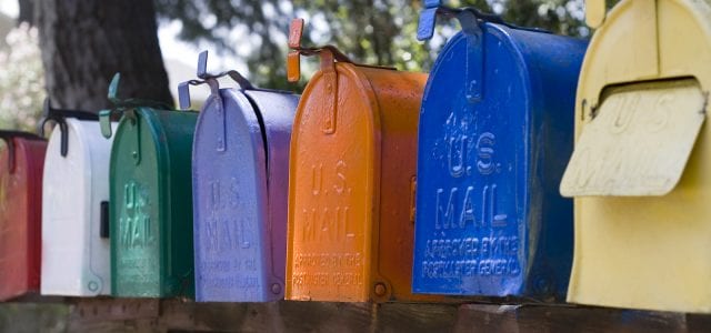 A row of multicolor mail mailboxes all have U.S. Mail stamped on the front.